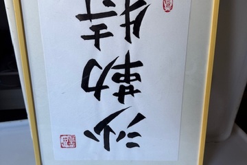 Afbeelding van ingelijste Oosterse kalligrafie in zwart op wit papier.  Het