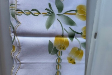 Afbeelding van wit tafelkleed met gele bloemenprint en sierbies.  Dit tafel